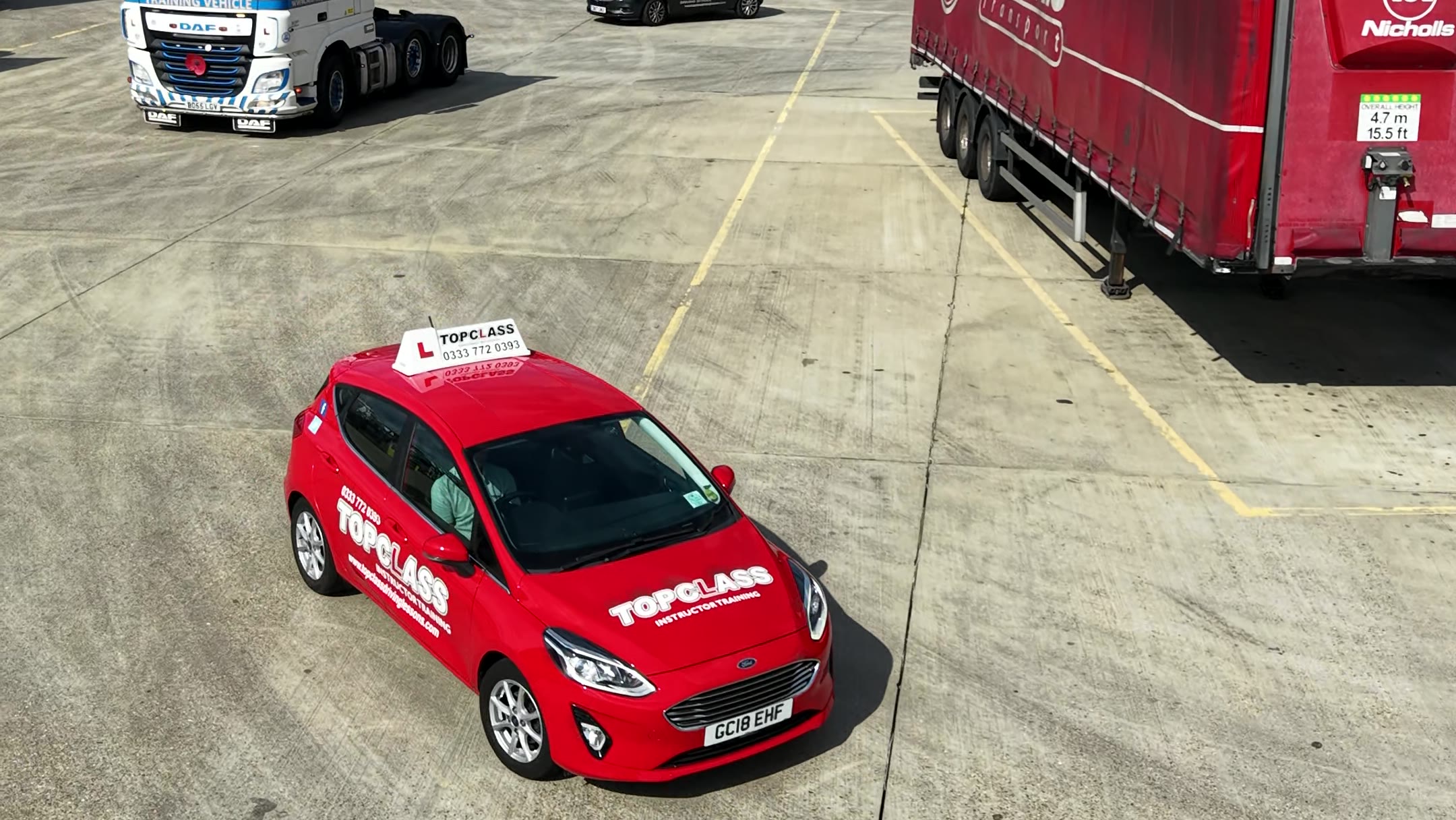 A red Topclass car driving across the yard