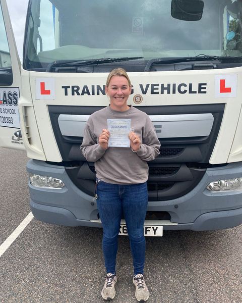 Alisha with a Class 2 pass certificate in front of a Learn2Pass training lorry