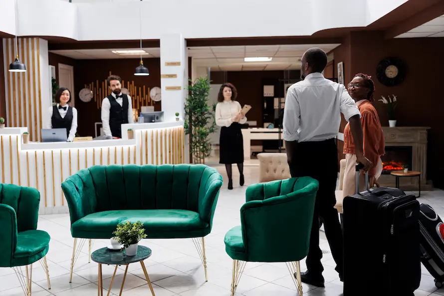 Modern hotel reception with guests arriving with suitcases and staff at the front desk