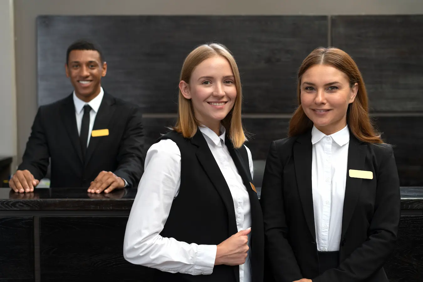 Hotel reception staff smiling at the front desk, representing professional customer service and a high-quality guest experience
