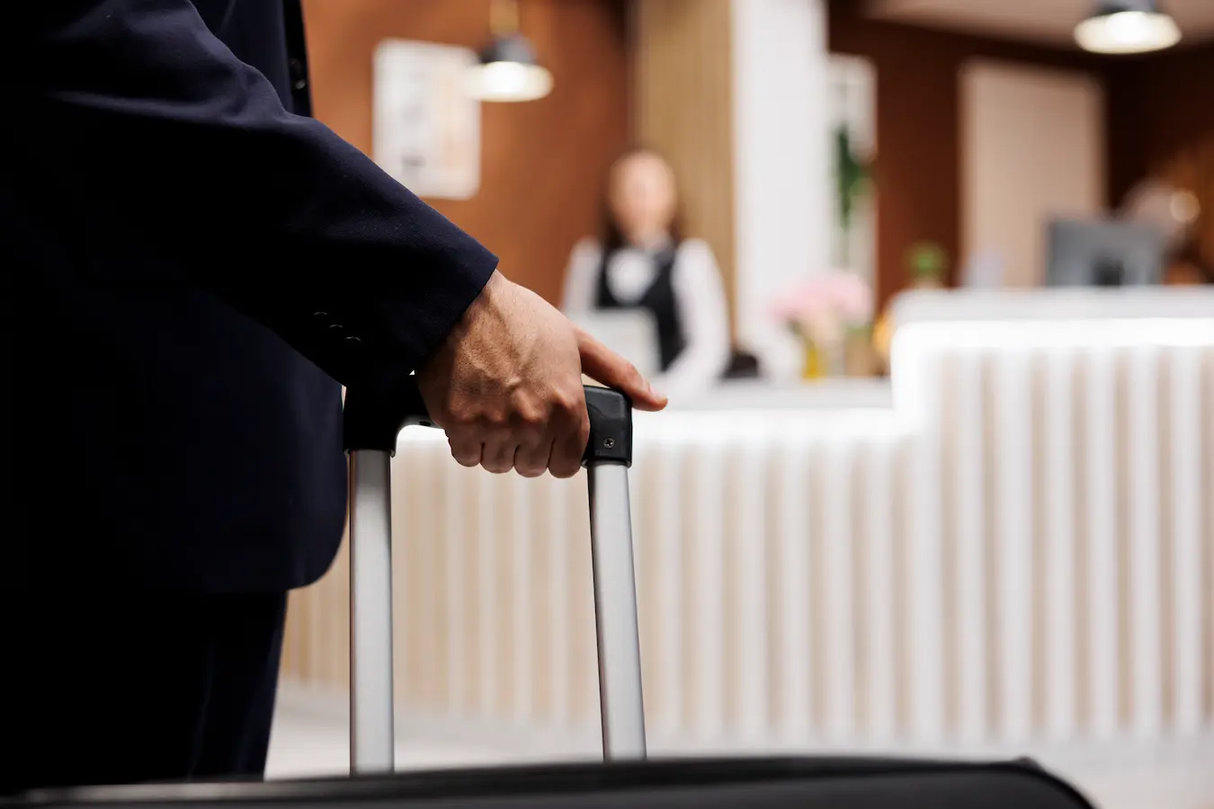Client arrivant à la réception d’un hôtel avec une valise, illustrant l’expérience d’arrivée