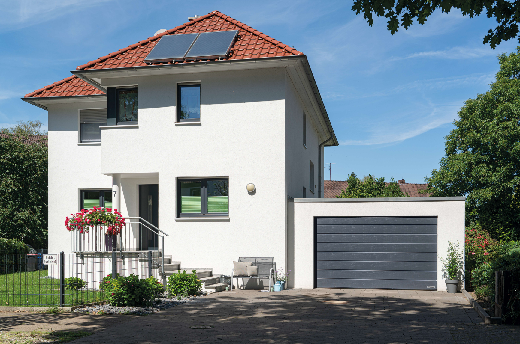 Garage mit einem kleinen Sektionaltor neben einem Haus