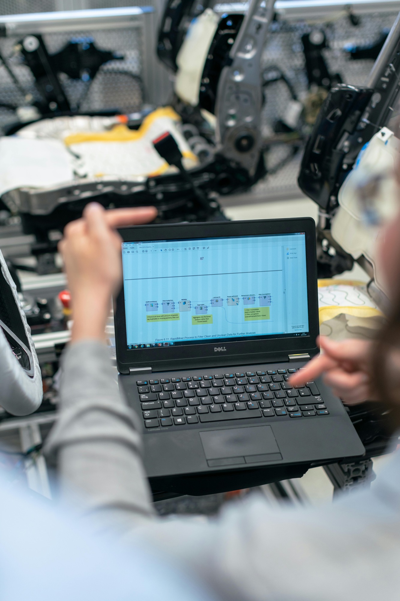 Engineer reviewing sensor data on a laptop at an automotive assembly line