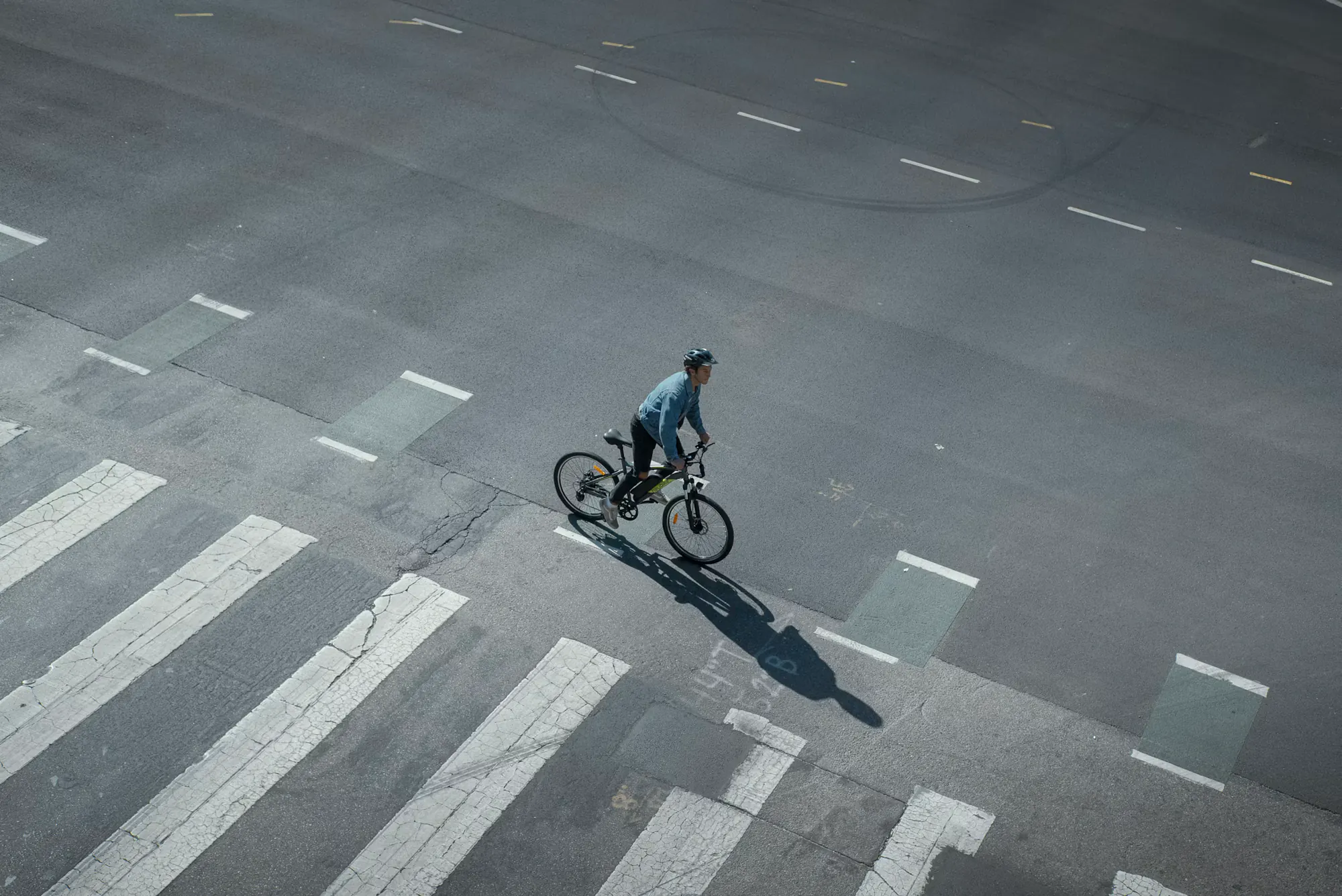 Cyclist crossing a city street, seen from above
