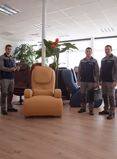 Trois techniciens Supra France debout dans un showroom moderne avec plusieurs fauteuils et une grande plante verte avec fleurs rouges.