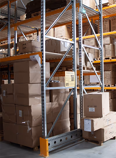 Rayonnage métallique avec plusieurs cartons empilés dans un grand entrepôt.