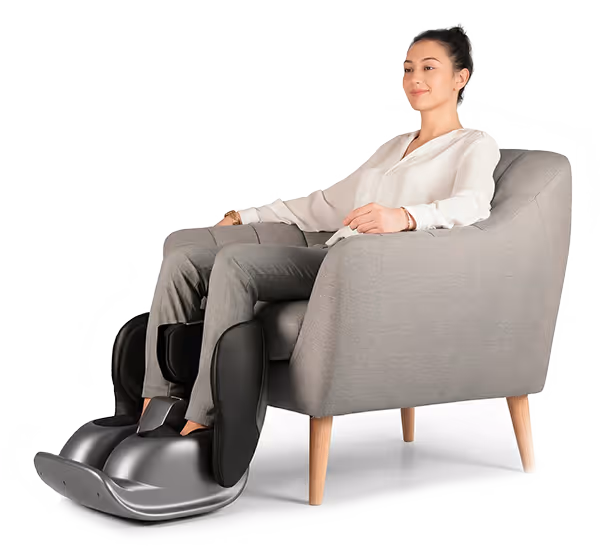 Femme assise sur un fauteuil gris utilisant un appareil de massage Pedimass pour les jambes et les pieds.