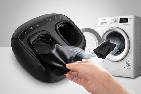 Main retirant une housse noire propre d'un appareil de massage des pieds avec une machine à laver en arrière-plan.