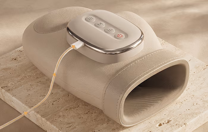 Appareil de massage Manova rechargeable avec câble USB sur surface beige.