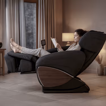 Femme détendue dans un fauteuil massant Évasion 3D, en position relax avec repose-pieds relevé, lisant dans une ambiance chaleureuse.