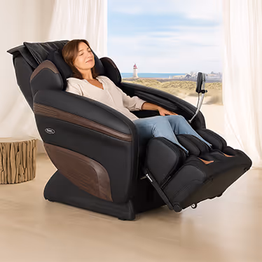 Femme détendue dans un fauteuil massant Mediform noir et bois, en position relax face à la mer pour un moment de bien-être