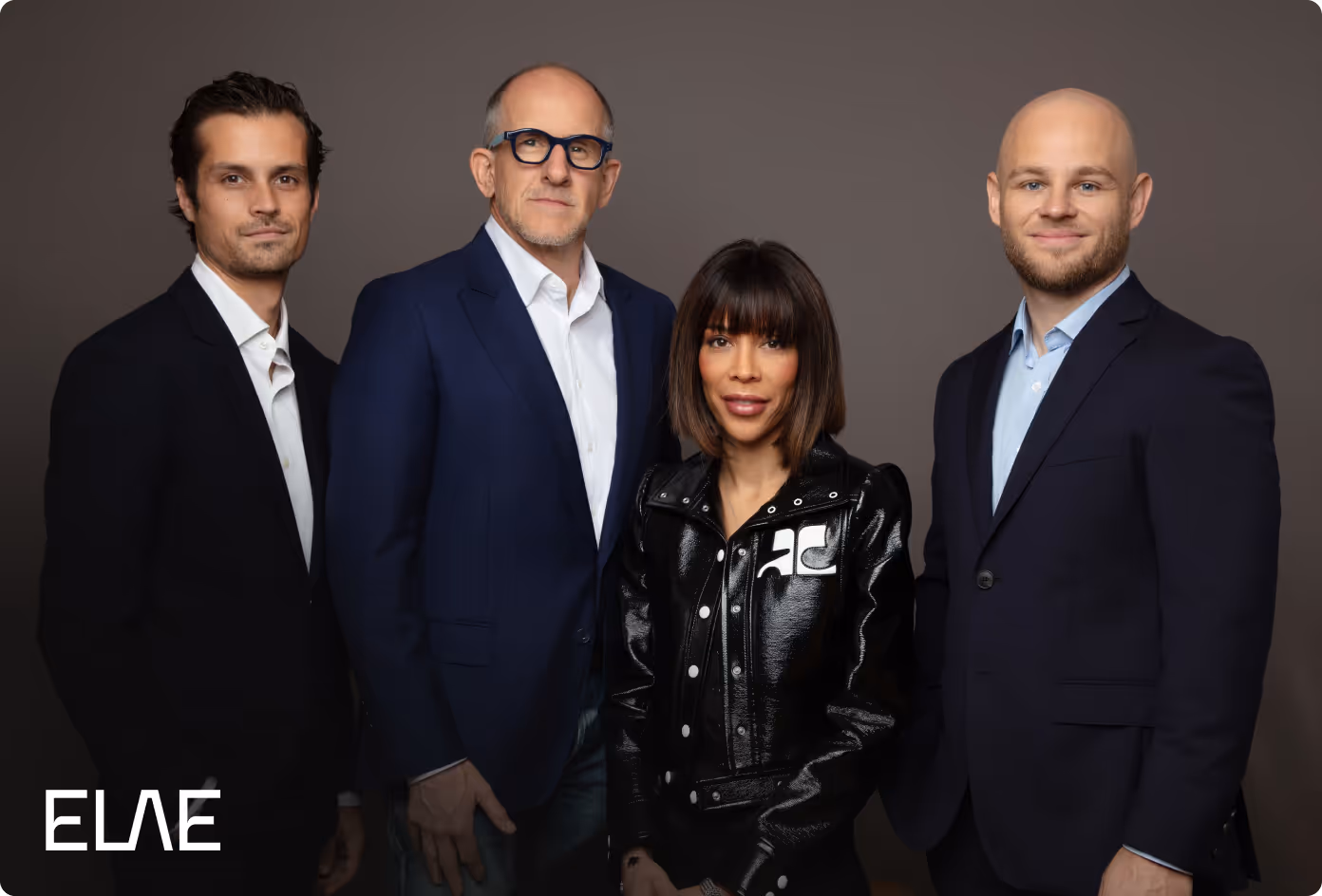 Groupe de quatre personnes professionnelles posant devant un fond uni, trois hommes en costume et une femme en veste noire brillante.
