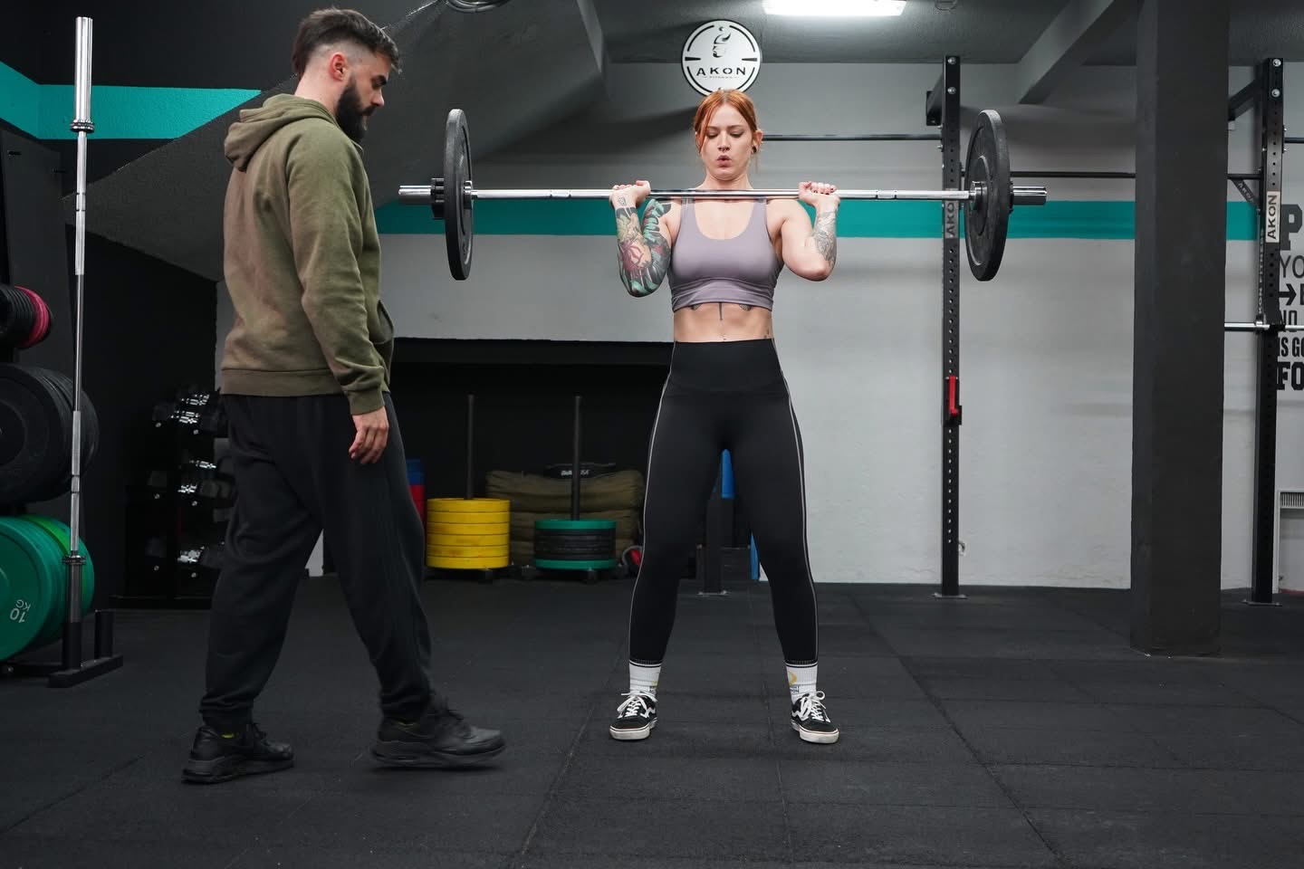Gabri Sáez, entrenador personal en Madrid, supervisando a una clienta durante un ejercicio de fuerza con barra en el gimnasio