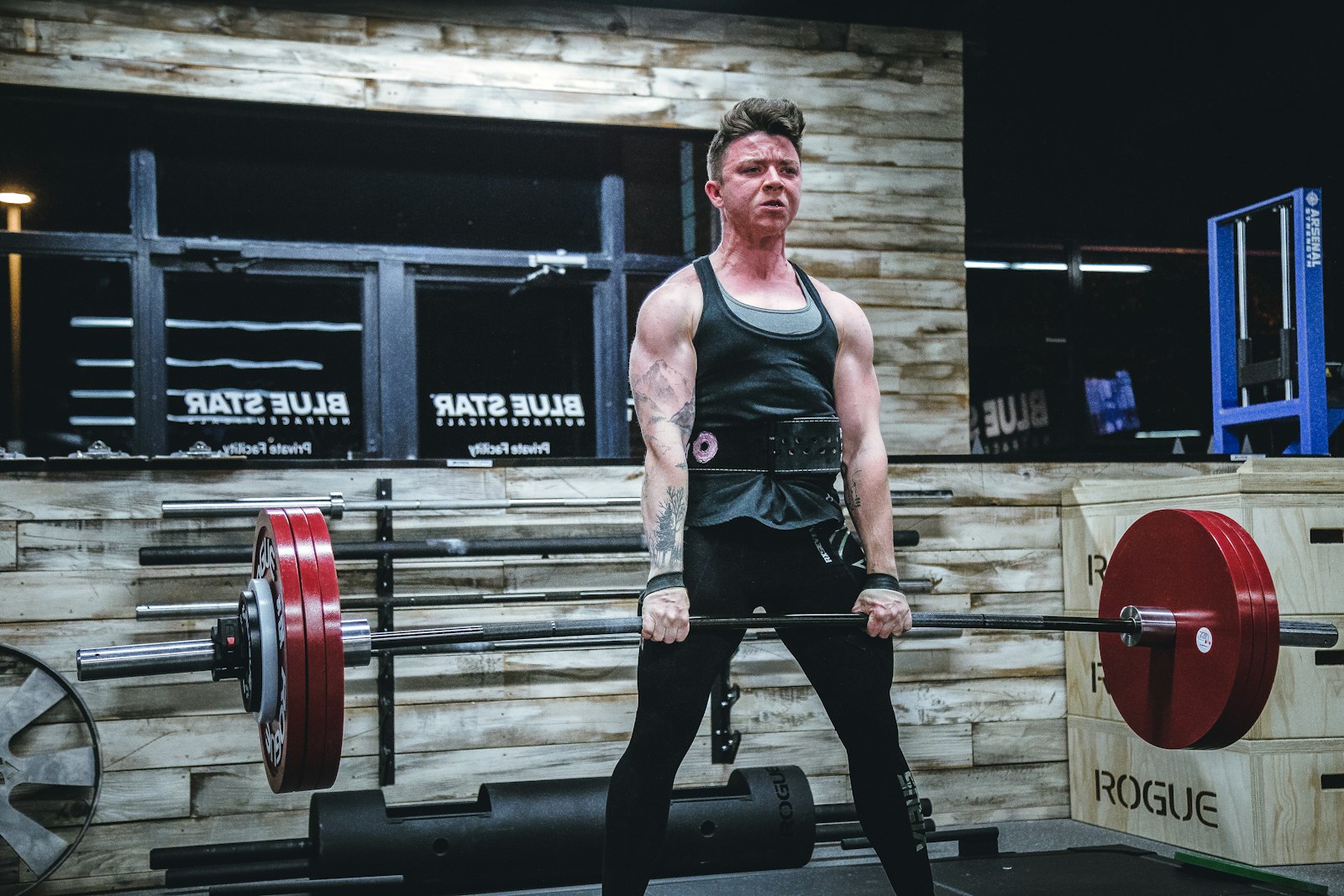 Hombre levantando una barra con la espalda recta en un gimnasio