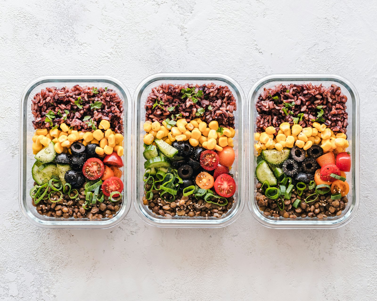 Tres recipientes de cristal con comida preparada: arroz, legumbres y verduras