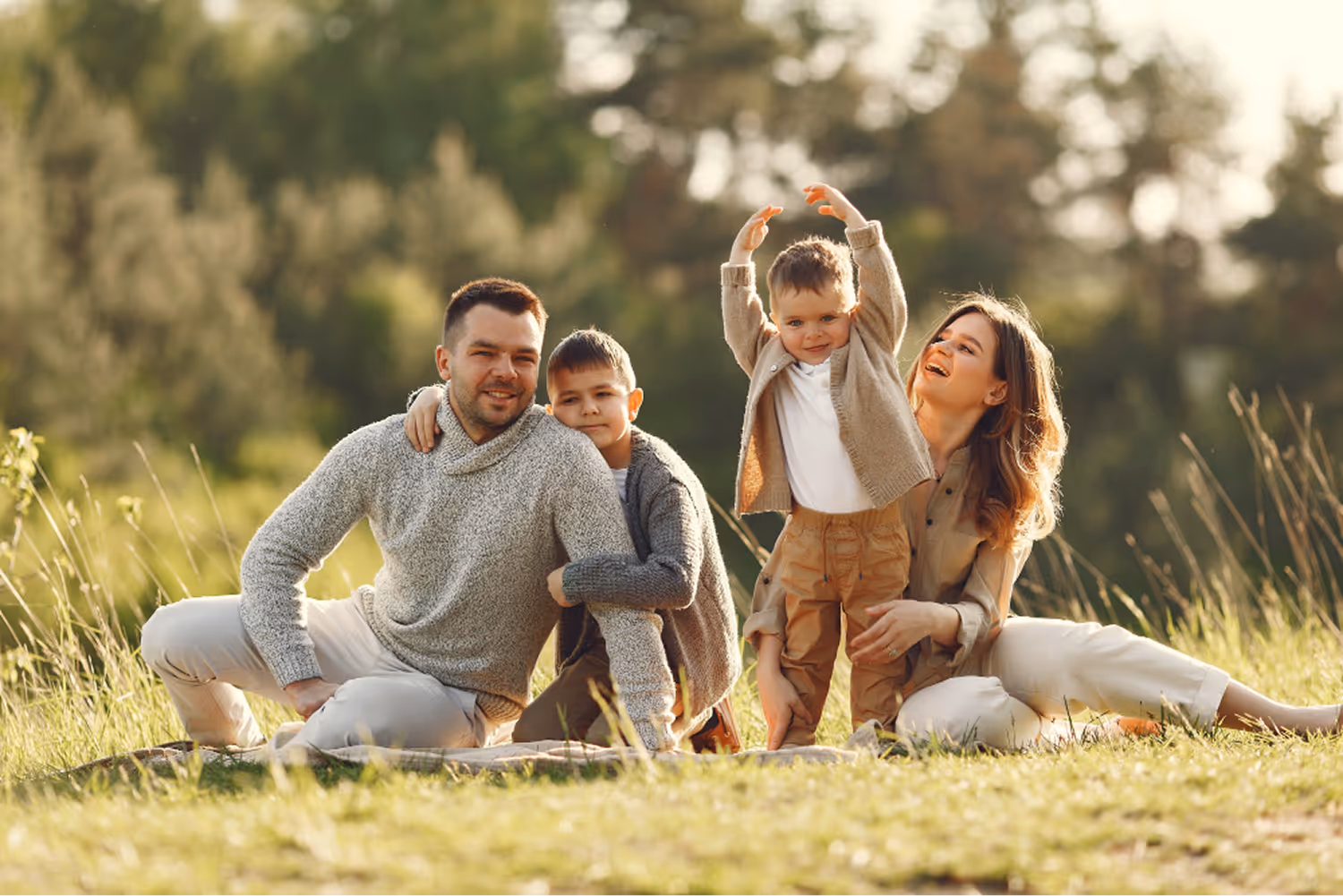 Glückliche Familie mit zwei Kindern sitzt und spielt an einem sonnigen Tag auf einer Wiese.