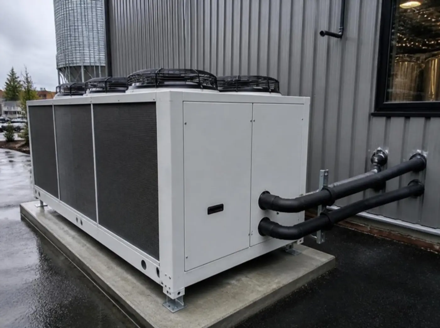 Outdoor glycol chiller with insulated piping beside a brewery