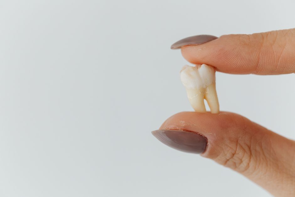 Patient wincing from tooth sensitivity while drinking a cold beverage, highlighting causes and remedies for sensitive teeth.