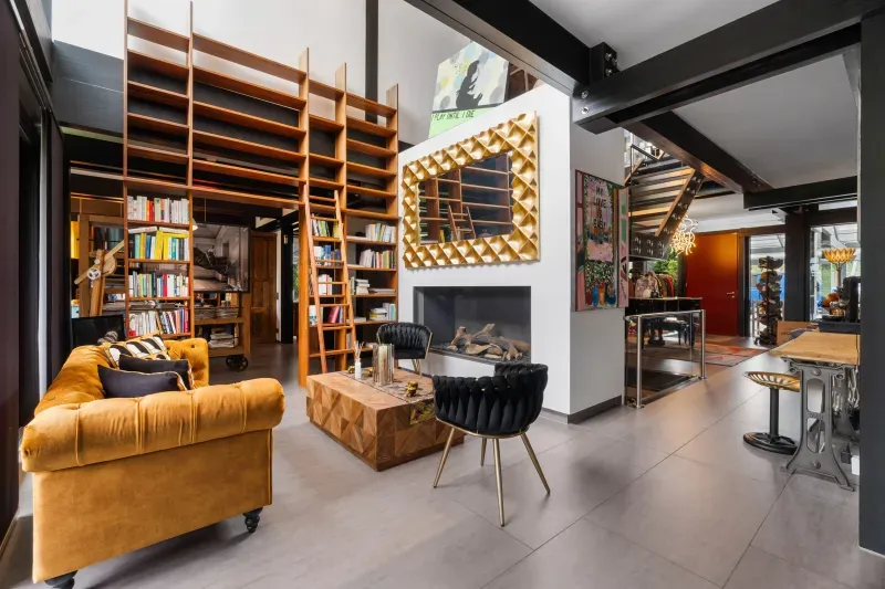 Wohnbereich mit Bücherregal, Kamin und Ledersofa