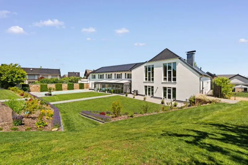 Gartenansicht eines Einfamilienhauses mit Wintergarten