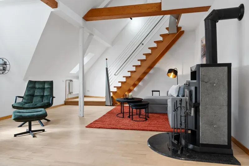 Wohnbereich mit Kaminofen, Treppe zur Galerie und Holzbalken