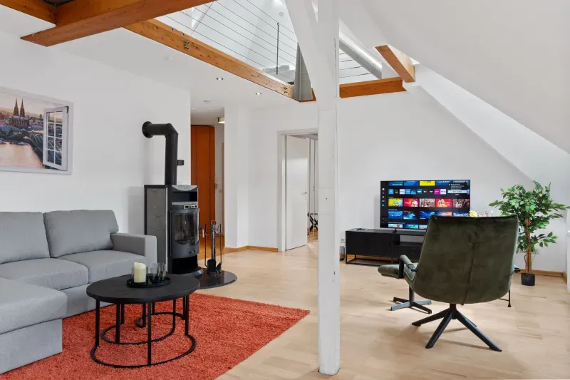 Dachgeschosswohnung mit Kaminofen, Sofa und Sichtbalken