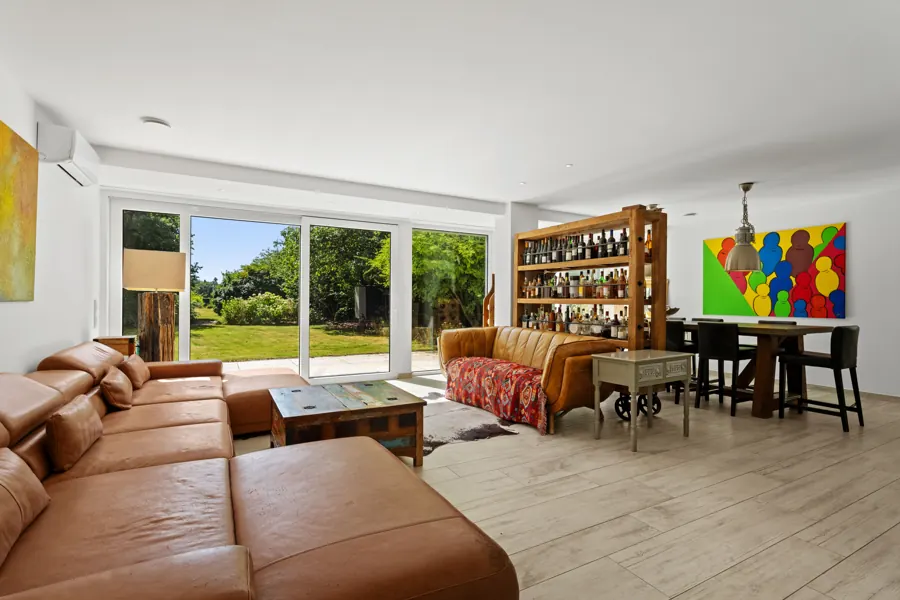 Helles Wohnzimmer mit Ledersofa und Blick in den Garten