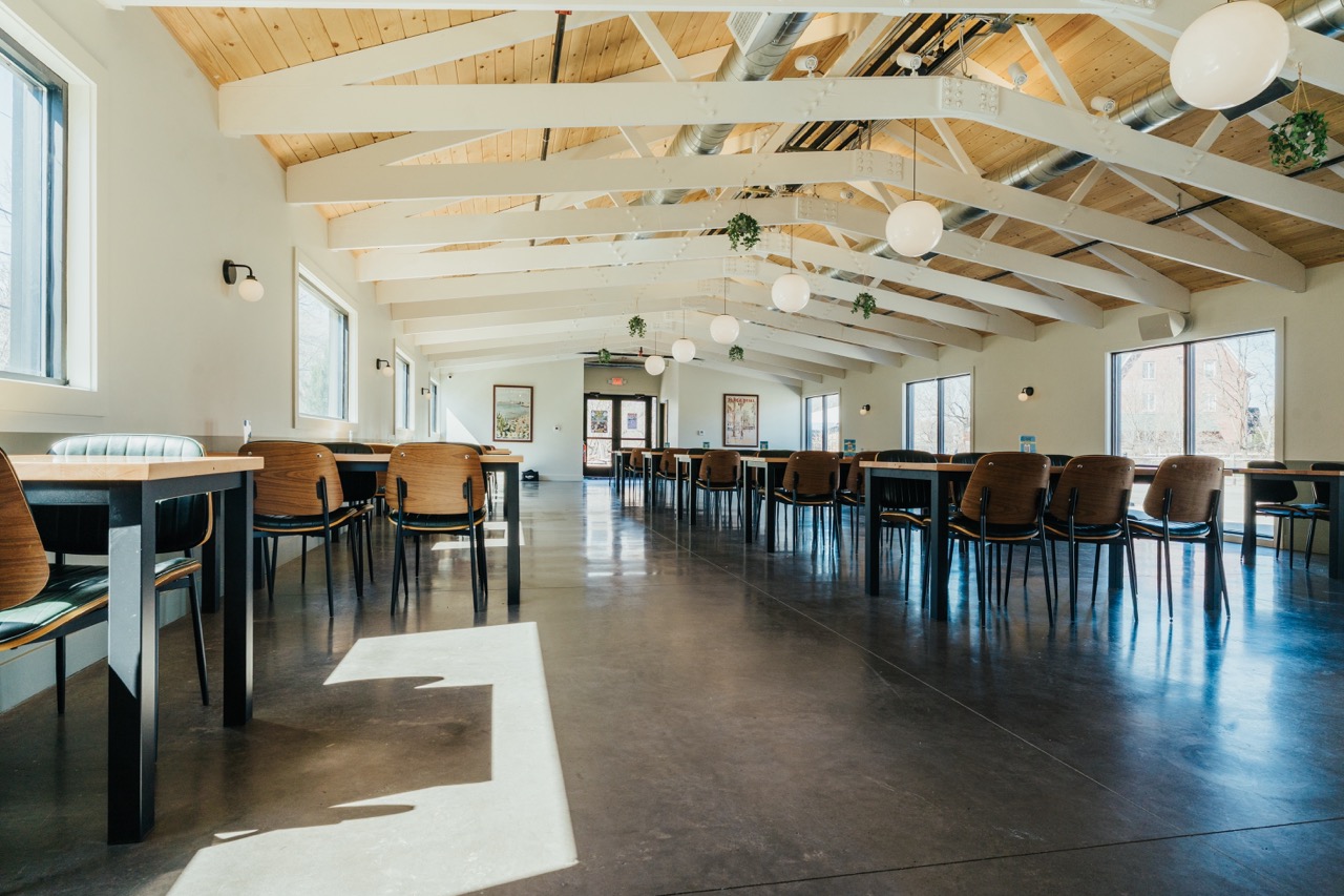 Modern brewery and restaurant interior at DeWolf Brewing in Victor, NY with high ceilings, natural light, and spacious seating