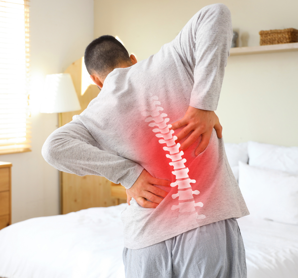 Man in gray shirt holding his lower back with illustrated spine and red area indicating back pain.