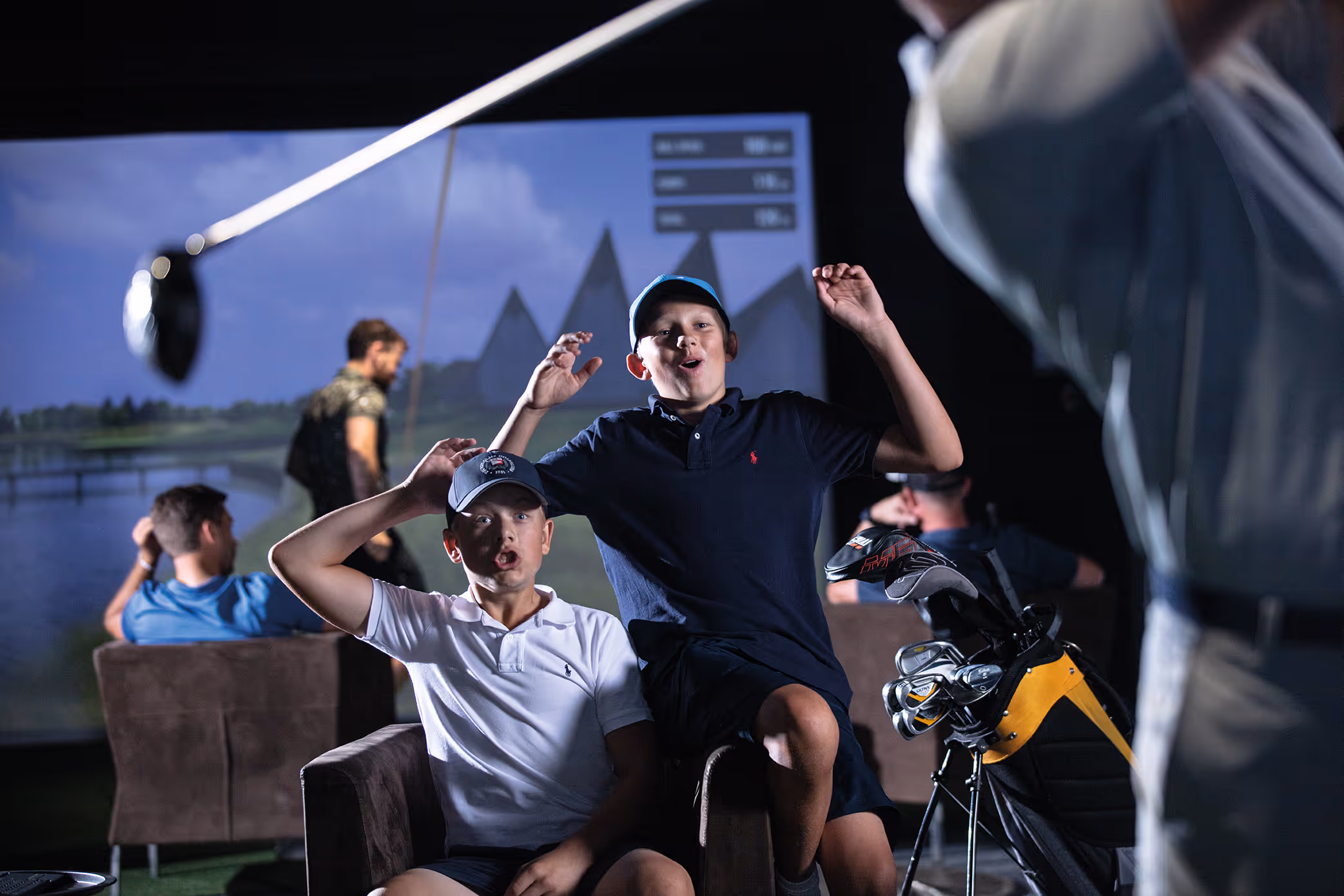 Two young players cheering on a golfer during his swing.