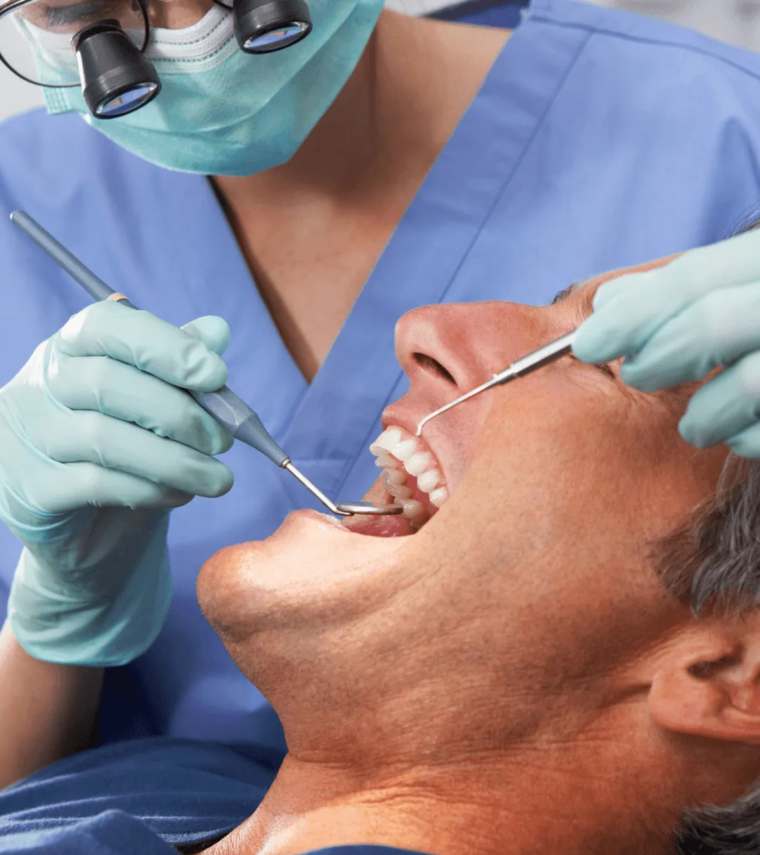 Dentist using mirror on male patient.