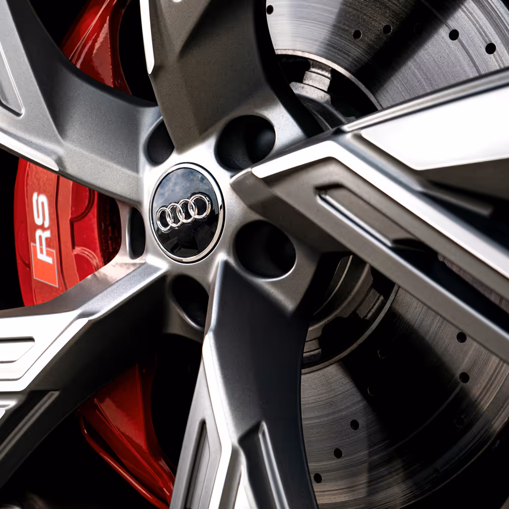 Detail close-up of Audi RS alloy wheel and red performance brake caliper, precision automotive photography by Roe Photo.