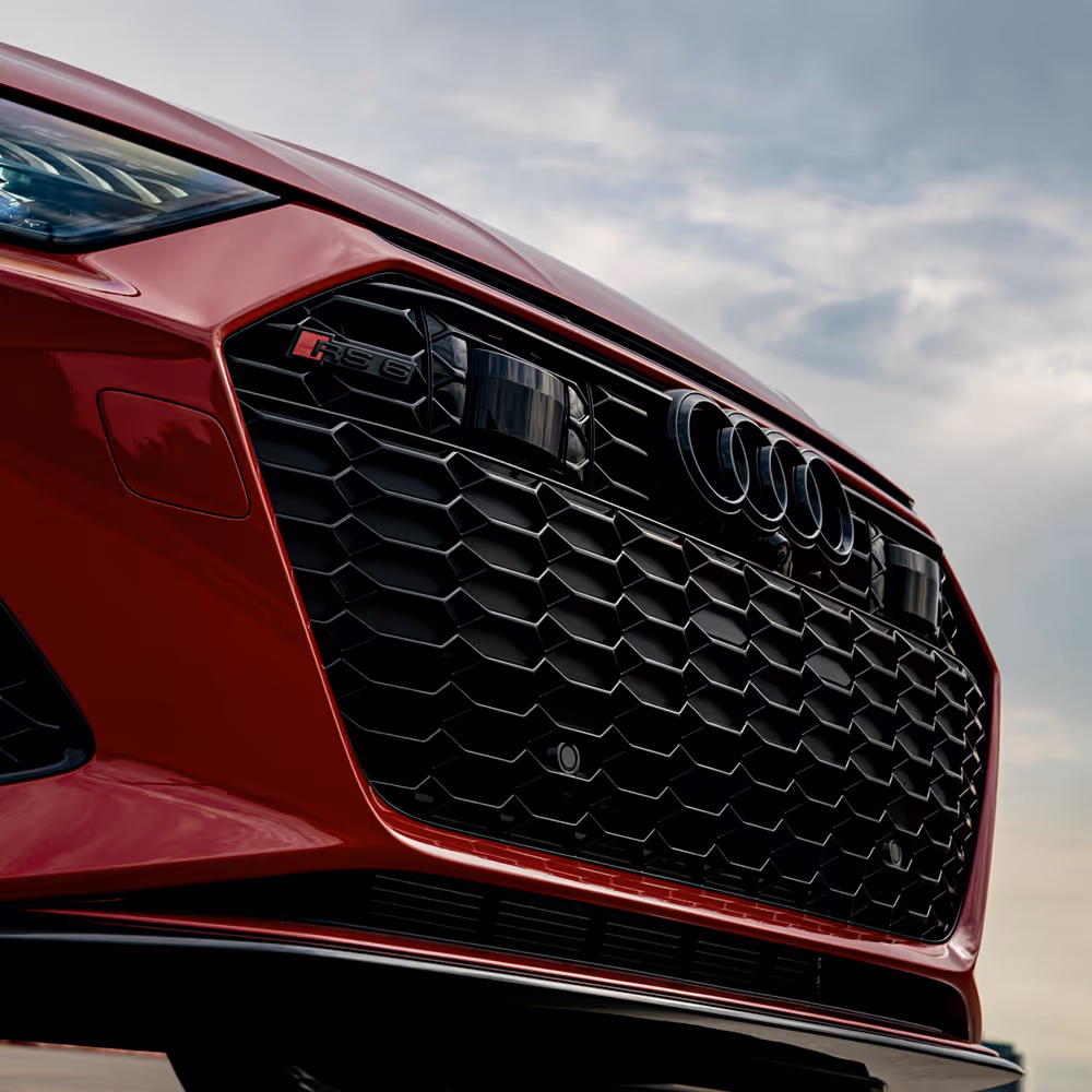 Low-angle view of red Audi RS6 grille and emblem, high-performance automotive photography by Roe Photo.