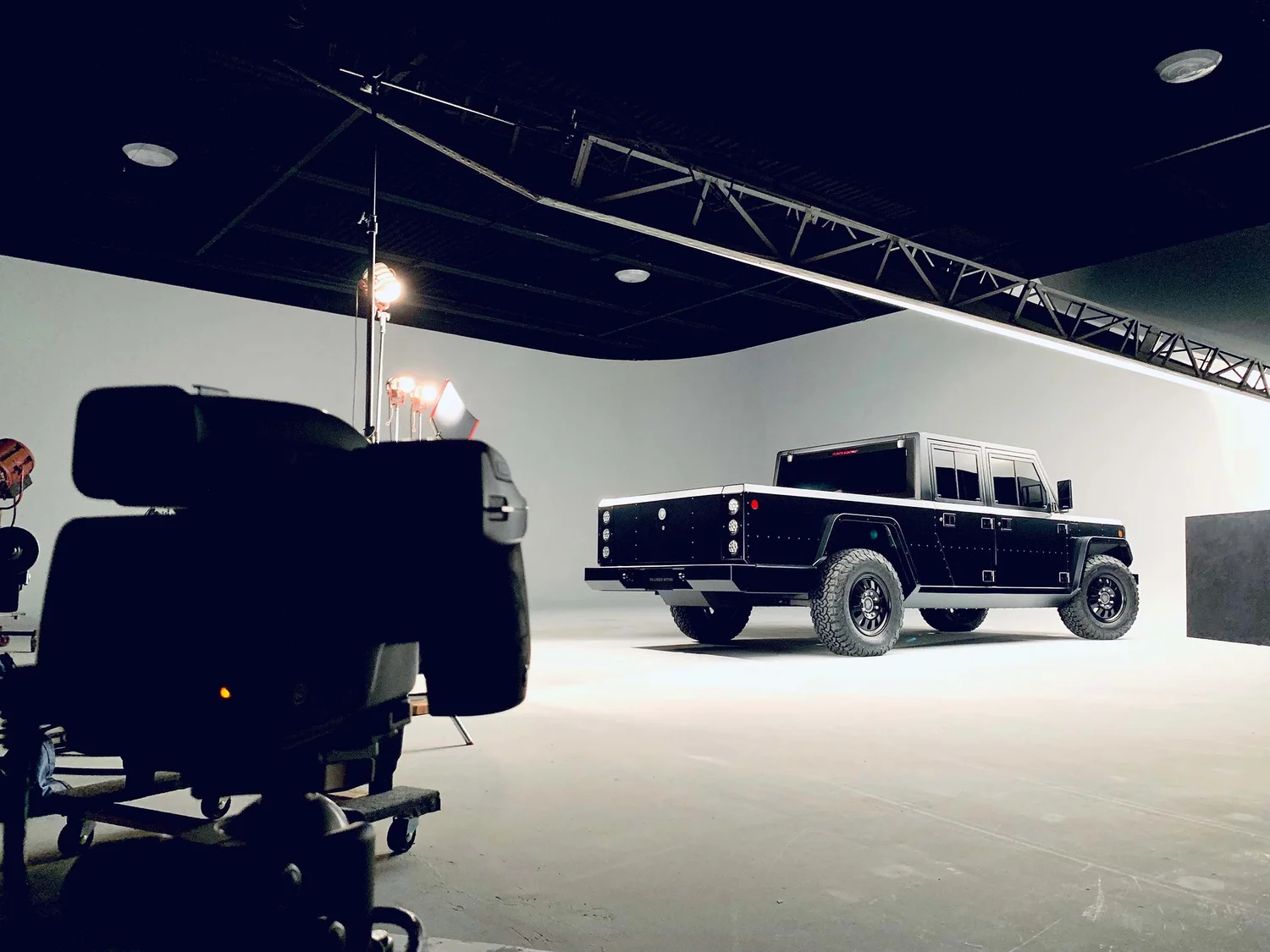 Commercial truck photography session in Detroit studio, Bollinger B1 pickup under soft studio lights with camera rig in foreground.