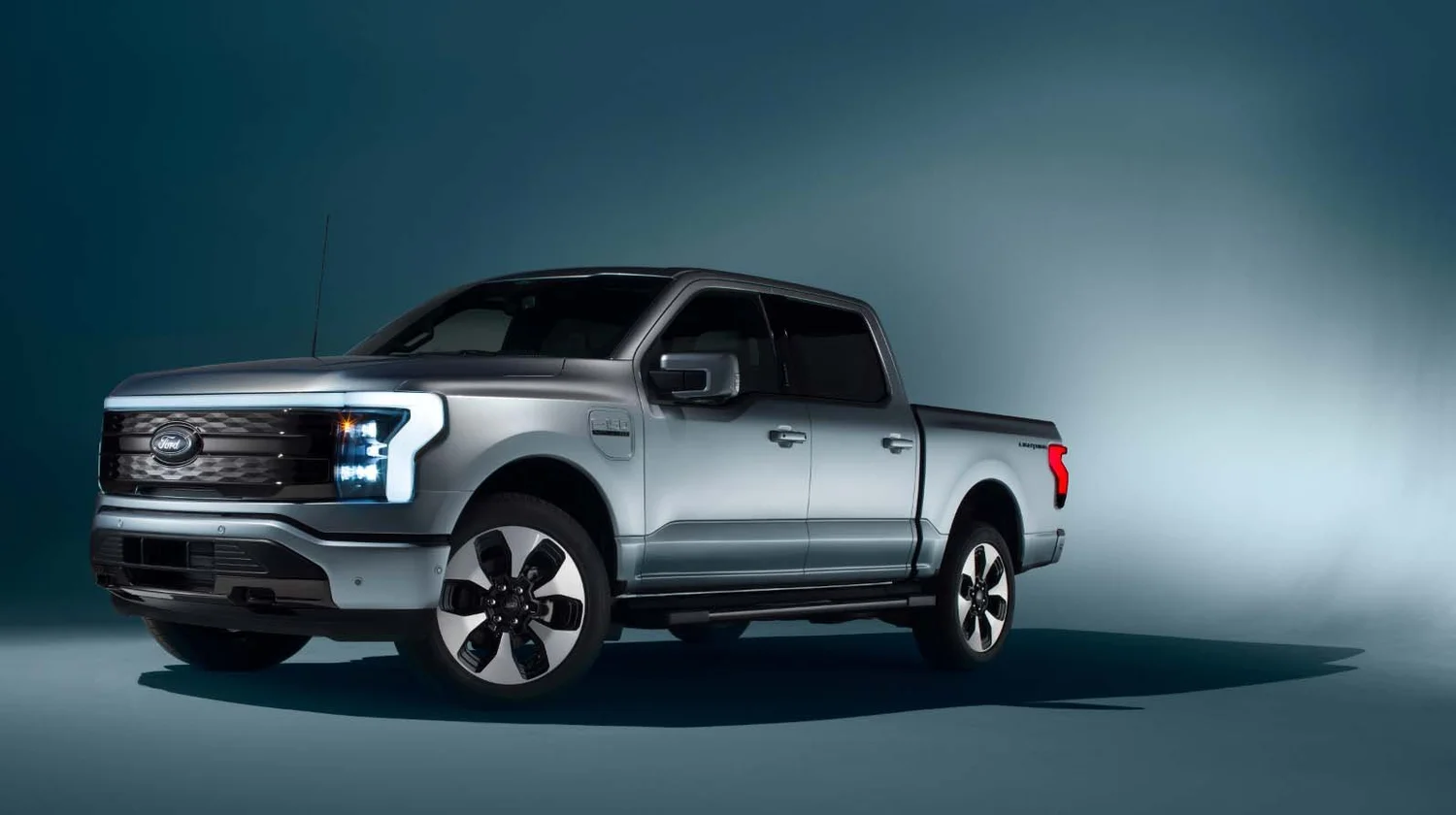 Studio automotive photo of silver Ford F-150 Lightning pickup, lit with soft gradient background for commercial campaign shoot.