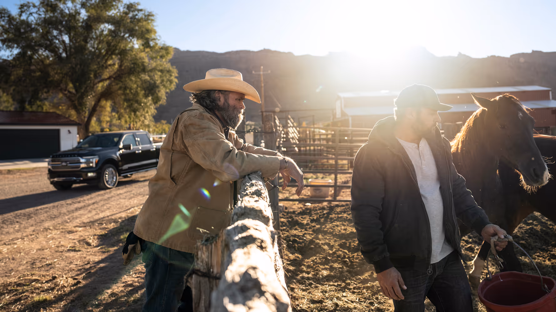 Ranchers working beside pickup truck and horse at sunrise, authentic lifestyle automotive photography in natural light.