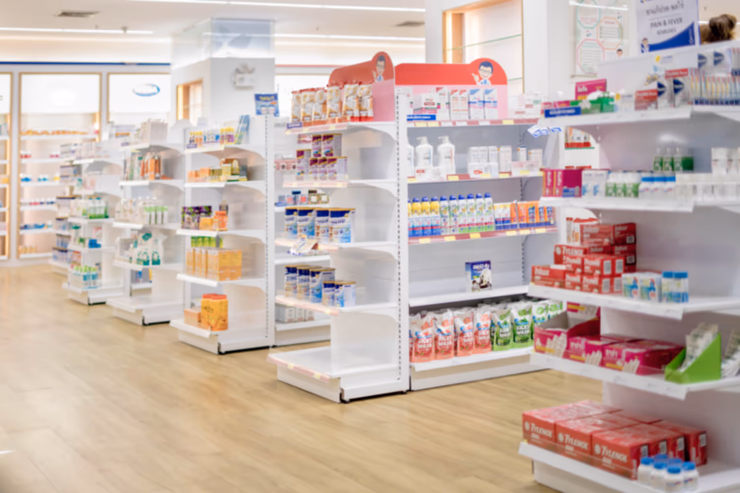 Bright pharmacy interior with neatly organized white shelves stocked with various healthcare and wellness products.