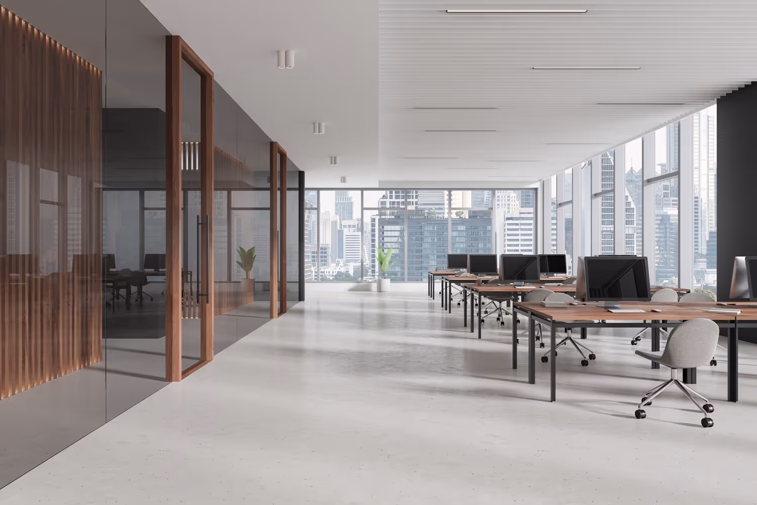Modern open office space with rows of desks, computer monitors, rolling chairs, large floor-to-ceiling windows, and city skyline views.