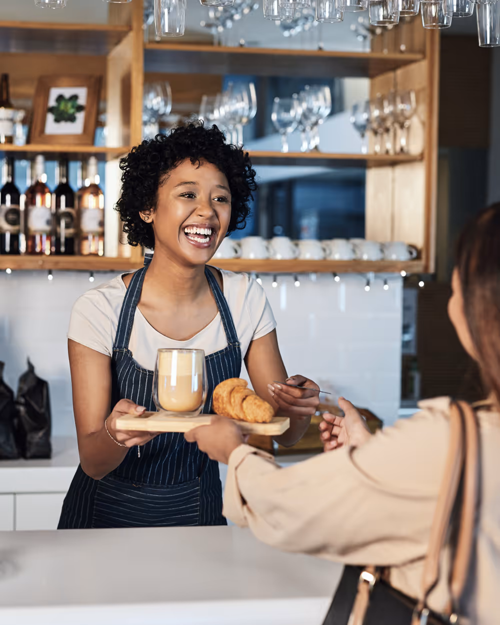 coffee shop owner is smiling and is handing over the coffee