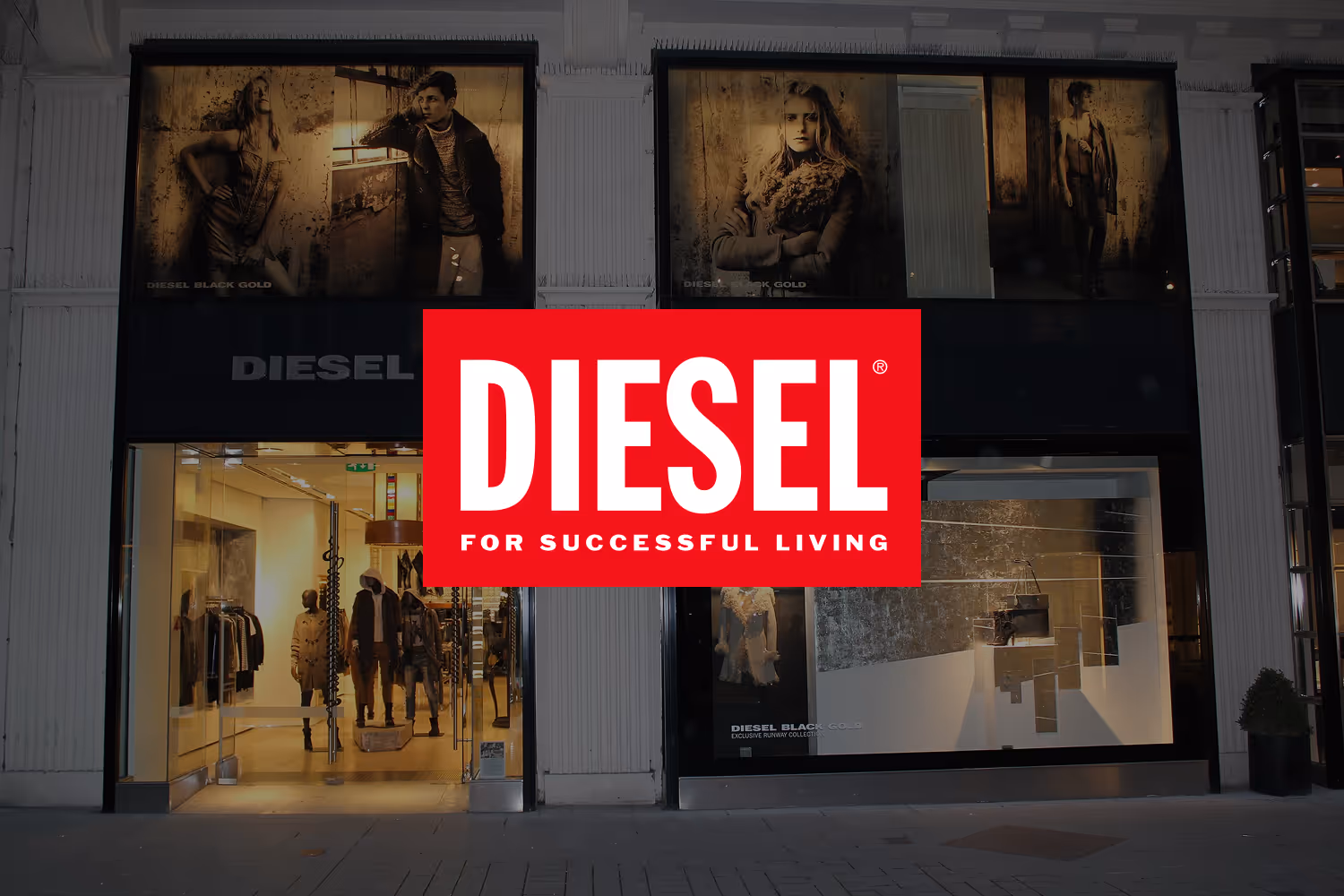 Diesel store front at night with illuminated mannequins and fashion ads above windows.