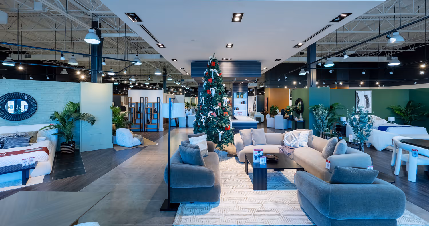 Modern furniture showroom featuring gray sofas around a coffee table with a decorated Christmas tree in the center.