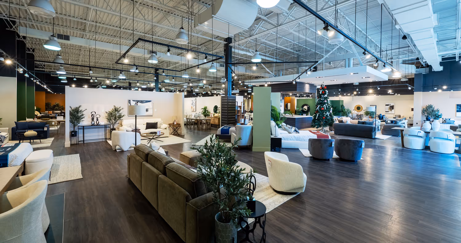 Wide view of a spacious furniture showroom with sofas, chairs, tables, and a decorated Christmas tree.
