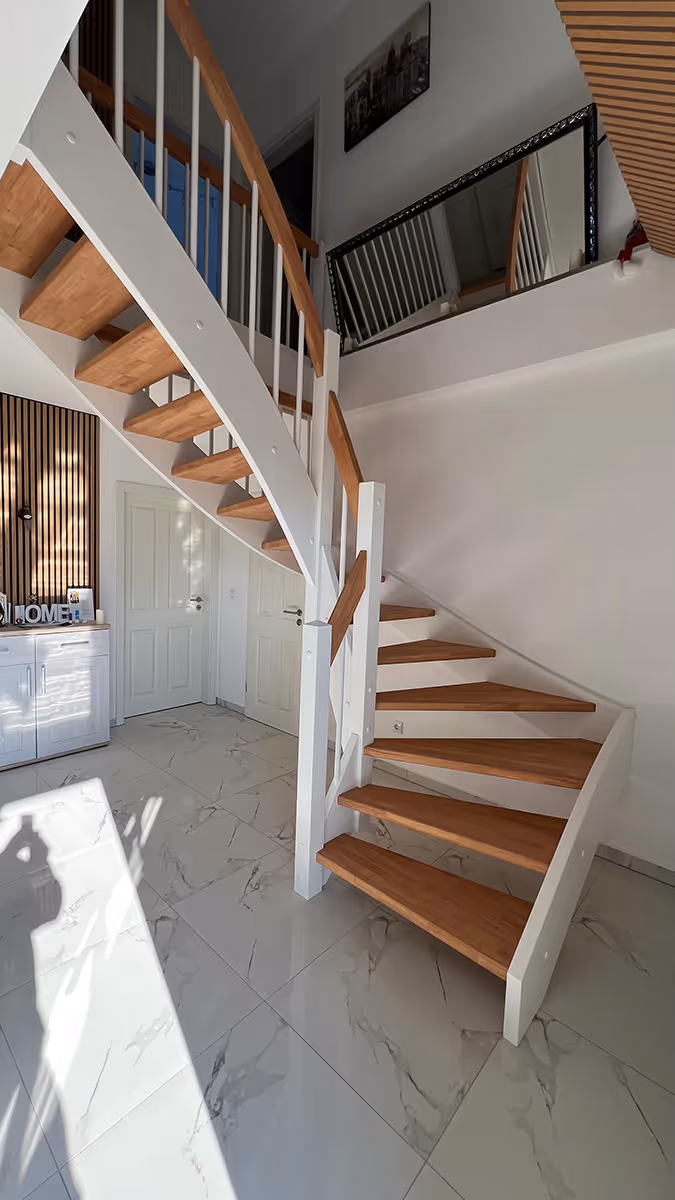 Moderne Treppe mit Holzstufen und weißem Geländer in einem hellen Flur mit Marmorboden.