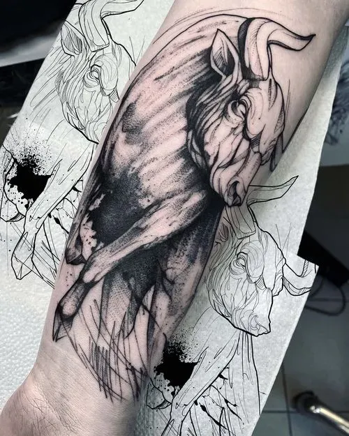 Black ink tattoo of a detailed bull with textured shading on forearm, surrounded by sketch-style bull drawings with ink splatters.