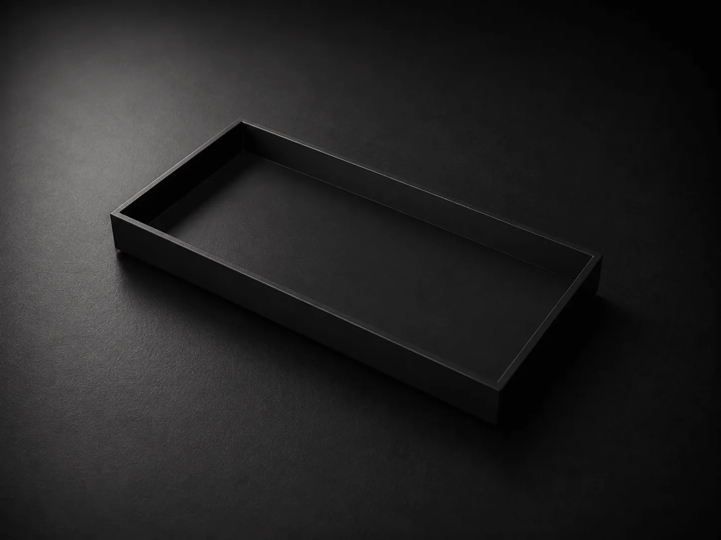 Minimalist black rectangular tray on a dark textured surface with soft lighting.