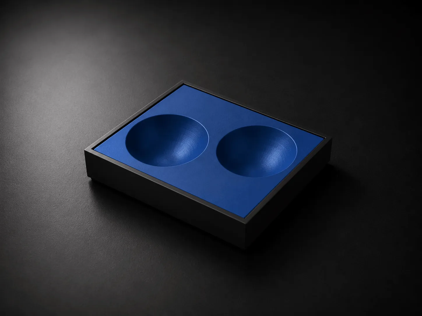 Black rectangular box with a blue insert featuring two shallow round depressions.