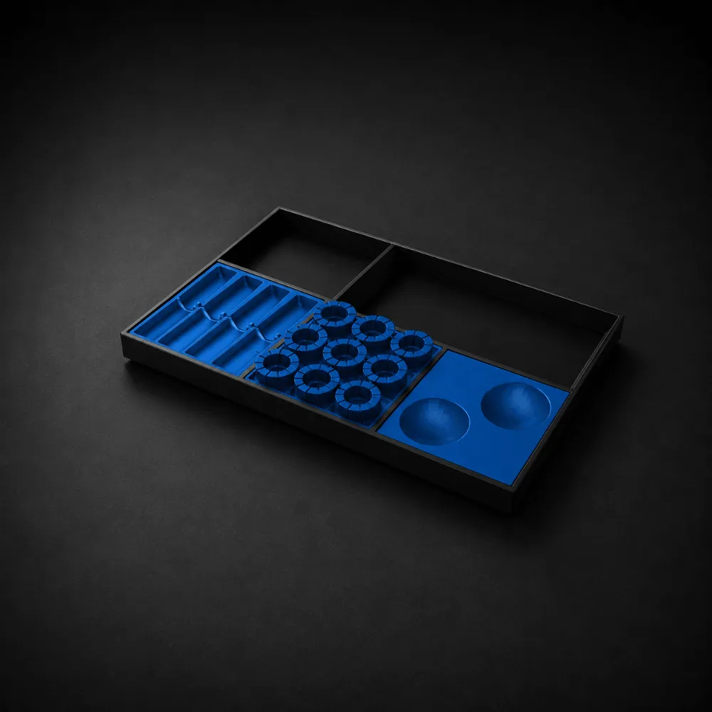 Black organizer tray with blue compartments of various shapes and sizes on a black surface.