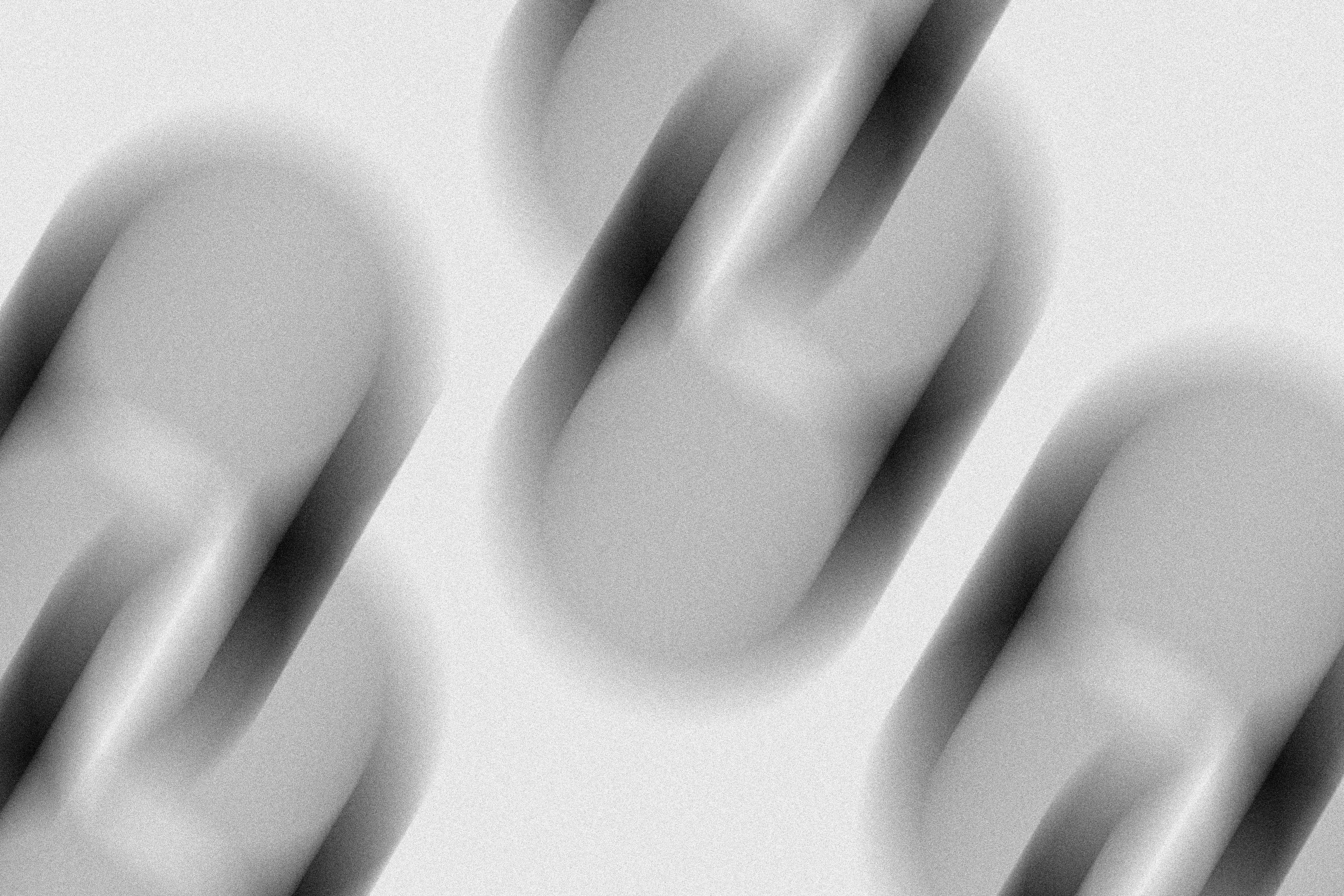 Monochrome close-up image of overlapping elongated oval shapes with soft edges and gradient shading.