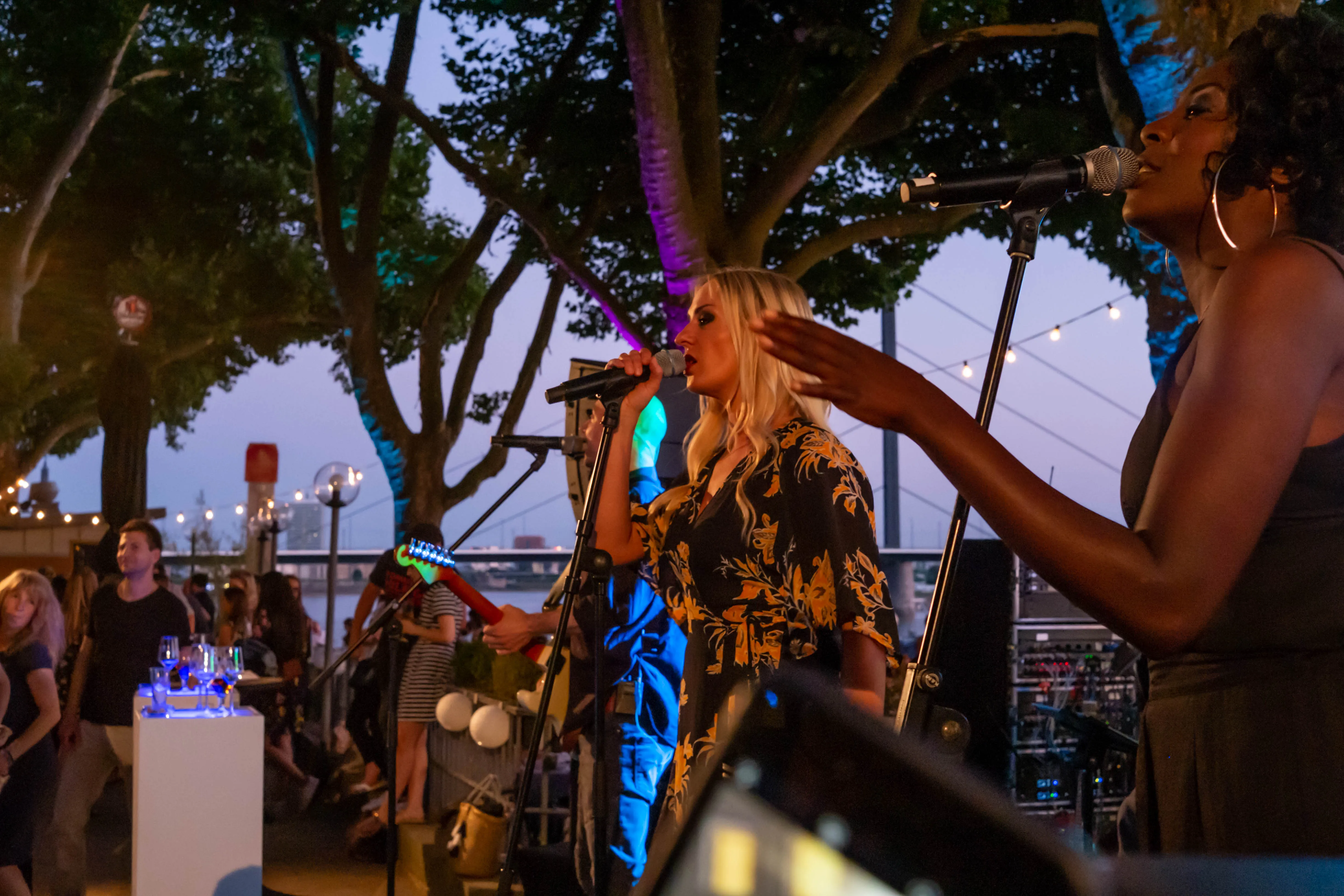 Nahaufnahme der beiden Sängerinnen der Hochzeitsband Gravity Live, die mit Leidenschaft und Energie auf einer Outdoor-Bühne in Düsseldorf singen.