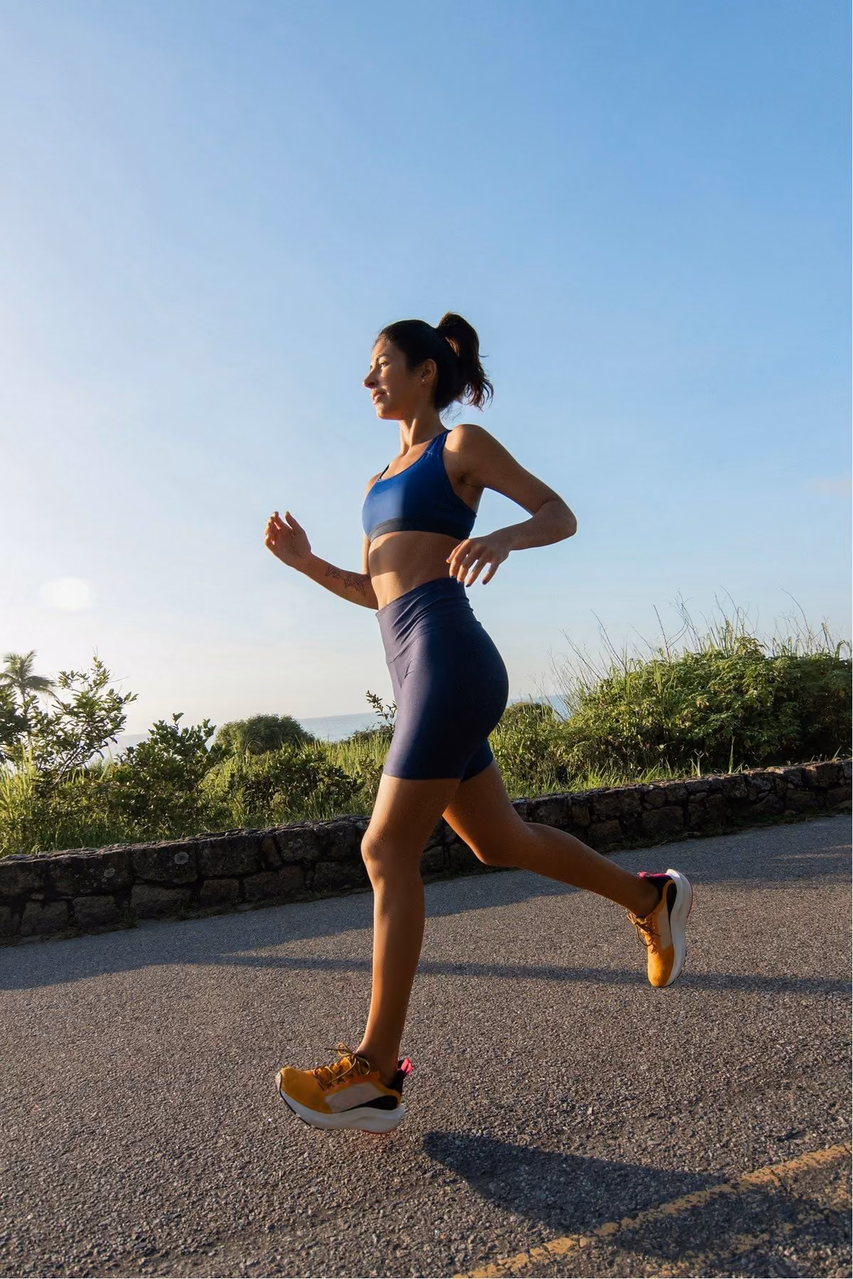 A woman in navy activewear running along a coastal road